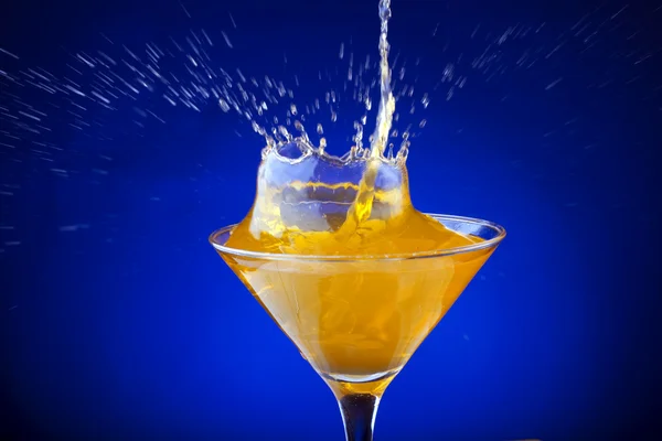 Skvätt apelsinjuice på blå bakgrund — Stockfoto