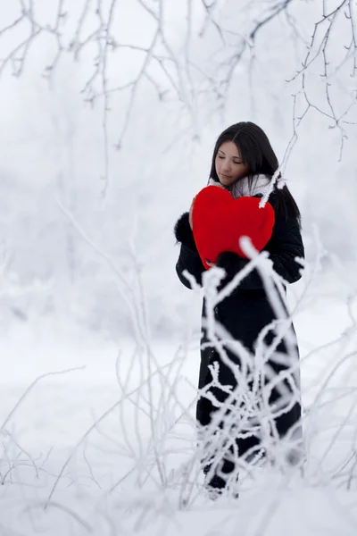 Hermosa chica en el bosque de invierno con el corazón rojo — Foto de Stock