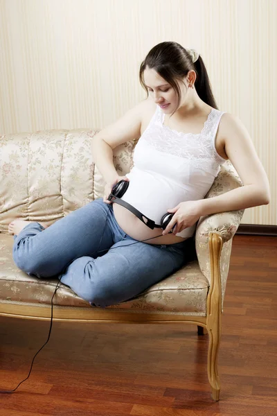 Hamile kadın kulaklıkla müzik dinliyor. — Stok fotoğraf