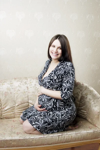 Έγκυος γυναίκα κάθεται σε έναν καναπέ της εκλεκτής ποιότητας — Φωτογραφία Αρχείου