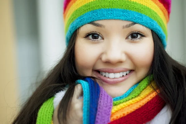 Chica en una bufanda y sombrero de colores arco iris Imagen de archivo