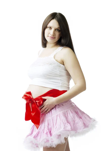 Kobieta w ciąży z czerwoną kokardą na brzuchu — Zdjęcie stockowe