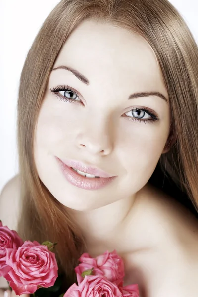 Vacker flicka på en vit bakgrund med rosor — Stockfoto