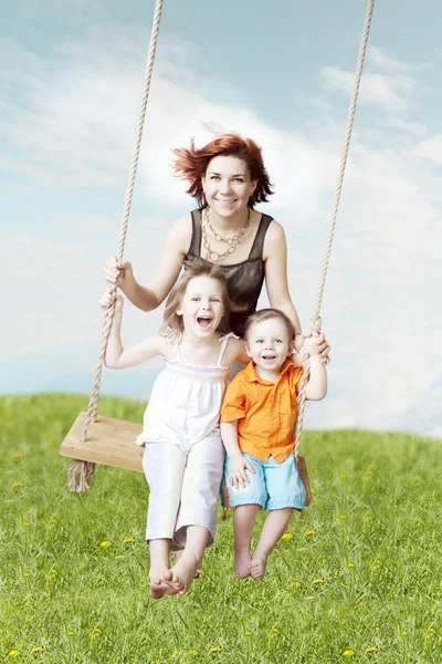 Familjen swing mot himlen och gräset — Stockfoto