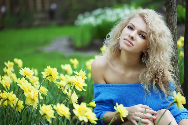 Piękny pozytywny dziewczyna w parku, w otoczeniu kwiatów — Zdjęcie stockowe