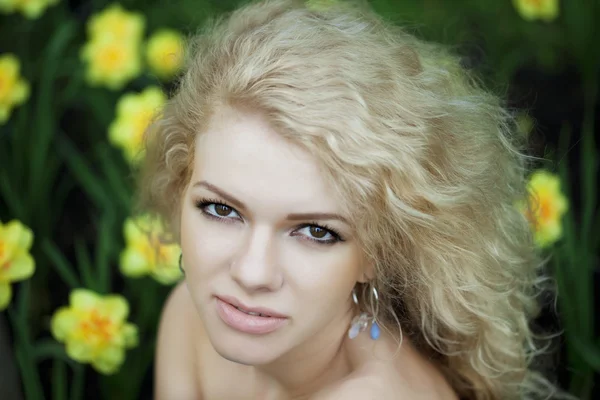 Hermosa chica positiva en un parque, rodeado de flores — Foto de Stock