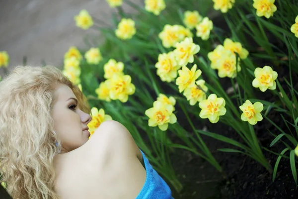Menina positiva bonita em um parque, cercada por flores — Fotografia de Stock