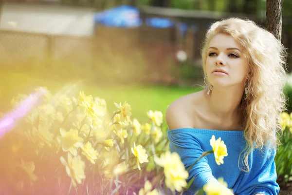 Piękny pozytywny dziewczyna w parku, w otoczeniu kwiatów — Zdjęcie stockowe