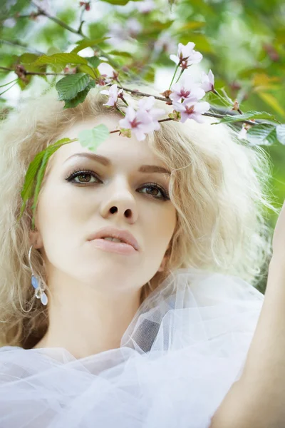 Schöne positive Mädchen in einem Park, umgeben von Blumen — Stockfoto