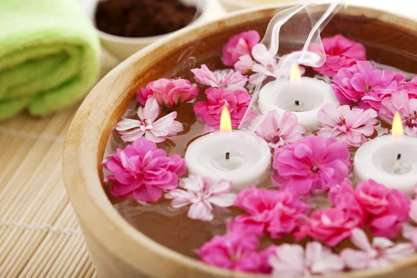 Terapia de spa, flores em água, em uma esteira de bambu . — Fotografia de Stock