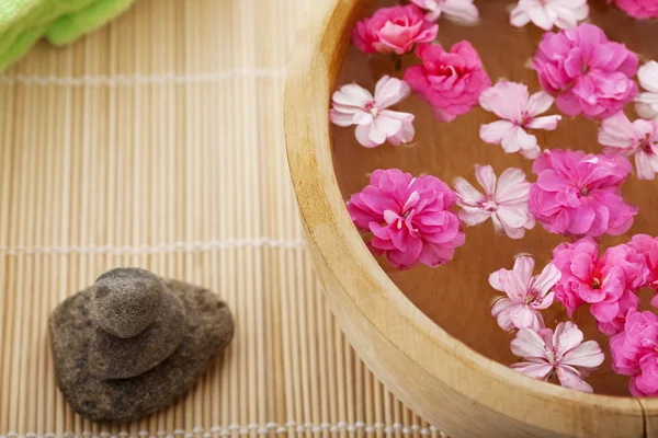 Terapia de spa, flores em água, em uma esteira de bambu . — Fotografia de Stock