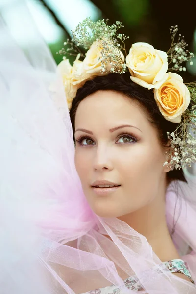 Όμορφη γυναίκα με ένα στεφάνι από τριαντάφυλλα — Φωτογραφία Αρχείου