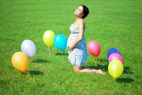 Έγκυος γυναίκα με μπαλόνια σε χόρτο — Φωτογραφία Αρχείου
