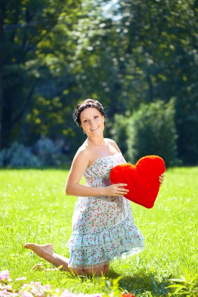 Красивая беременная женщина с красным сердцем — стоковое фото