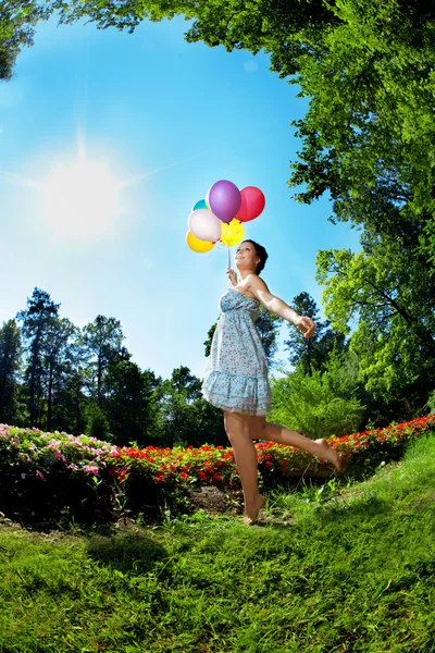 Mulher com balões na grama — Fotografia de Stock