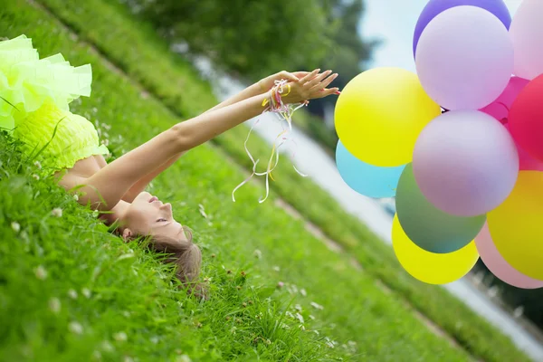 Woman holding bunch of colorful air balloons — Stock Photo, Image