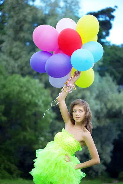 Mujer sosteniendo racimo de globos de aire de colores — Foto de Stock