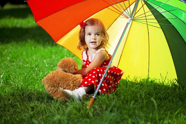 Kleines Mädchen mit Regenbogenschirm im Park — Stockfoto