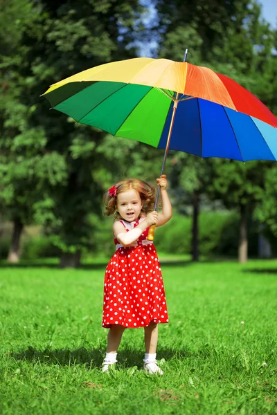 Niña con un paraguas de arco iris en el parque — Foto de Stock