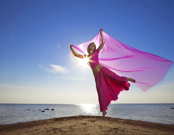 Menina bonita que saltar na praia ao pôr do sol — Fotografia de Stock