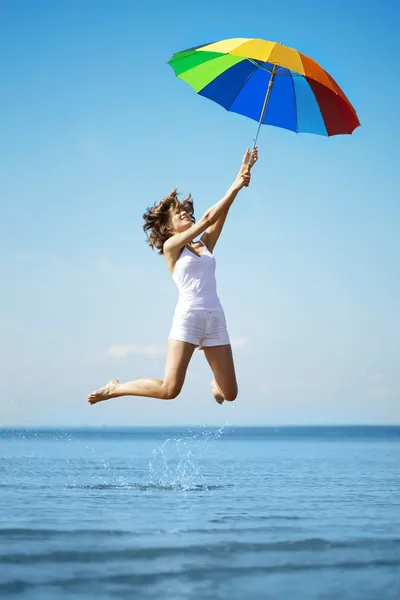 Girl jump with a rainbow umbrella — Stock Photo, Image
