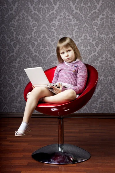 Девушка сидит в кресле с ноутбуком — стоковое фото