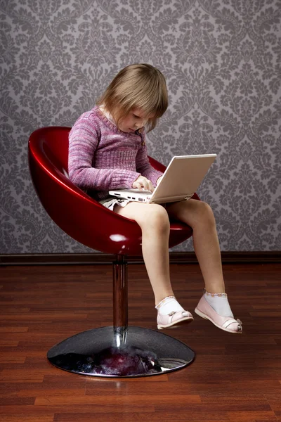 Menina sentada em uma cadeira com um laptop — Fotografia de Stock