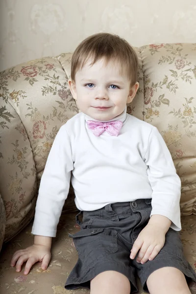 Aranyos kisfiú, a háttérben a vintage kanapé — Stock Fotó