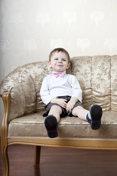 Menino bonito em um fundo de sofá vintage — Fotografia de Stock