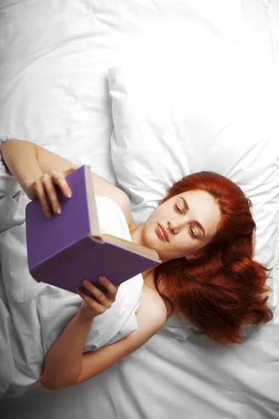 Žena, která čte knihu v posteli — Stock fotografie