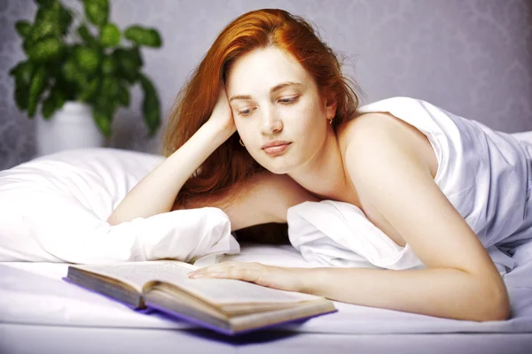 Kvinna som läser en bok i sängen — Stockfoto