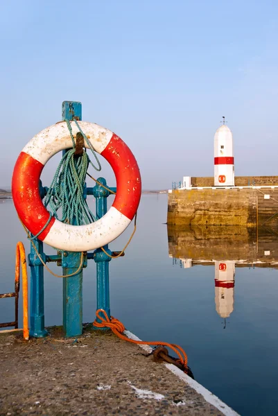 Bouée de sauvetage blanche et rouge dans le port avec phare — Photo