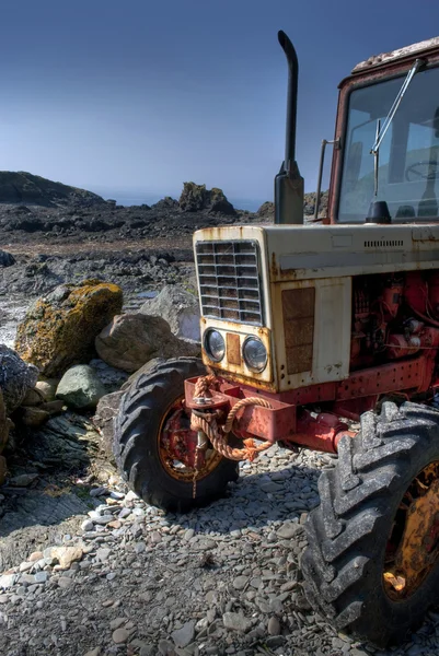 Partea din față a tractorului vechi, ruginit pe o plajă cu pietricele — Fotografie, imagine de stoc
