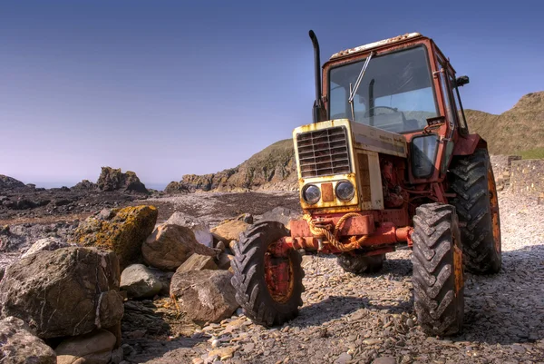 Stock image Old, rusty tractor on a pebble beach