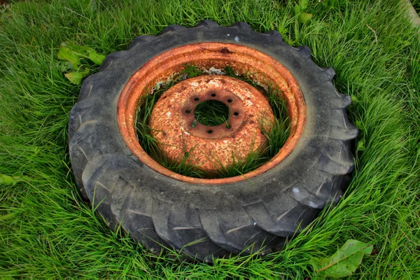 Neumático de tractor usado viejo oxidado en hierba —  Fotos de Stock