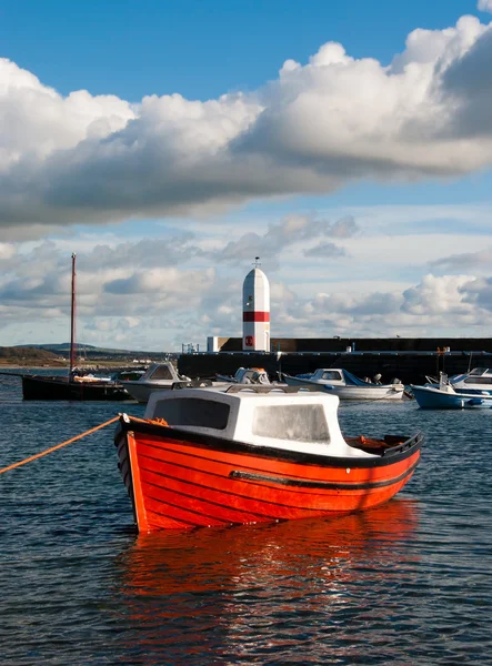 Маленькая рыбацкая лодка, связанная в гавани с маяком — стоковое фото