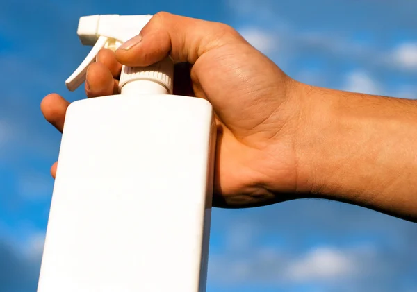 stock image Hand Holding a Spray Bottle Against Blue Sky