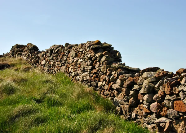 Viejo muro de piedra con hierba verde y cielo azul —  Fotos de Stock