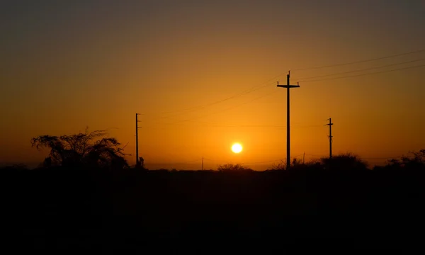 Pôr do sol sobre velhos pólos elétricos silhuetas — Fotografia de Stock