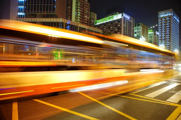 Rutas de luz de autobús borrosas y de alta velocidad en el paisaje nocturno del centro — Foto de Stock