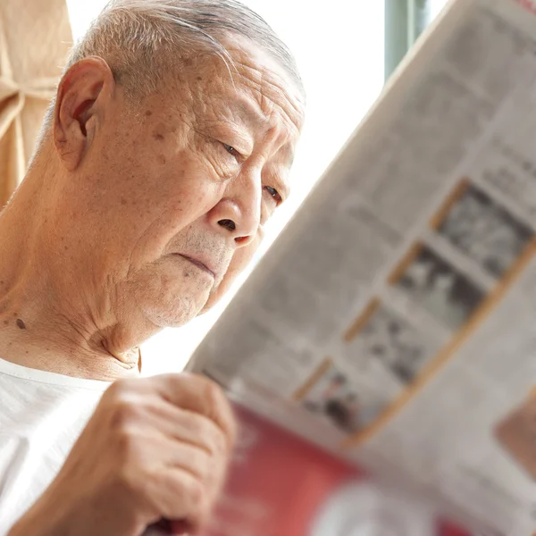 stock image A senior man is reading newspaper