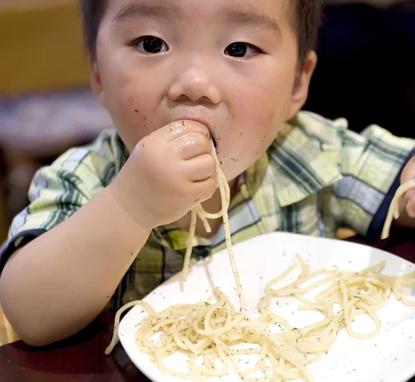 Baby essen, um nach Nudeln zu greifen — Stockfoto