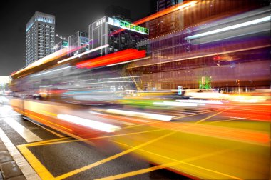 High speed and blurred bus light trails in downtown nightscape clipart