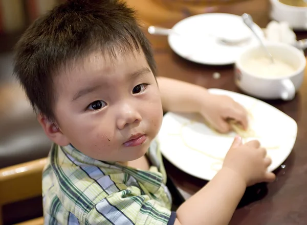 Baby essen, um Nudeln mit der Hand zu greifen — Stockfoto