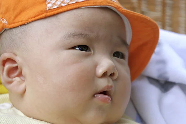 Bebê bonito com uma tampa laranja — Fotografia de Stock