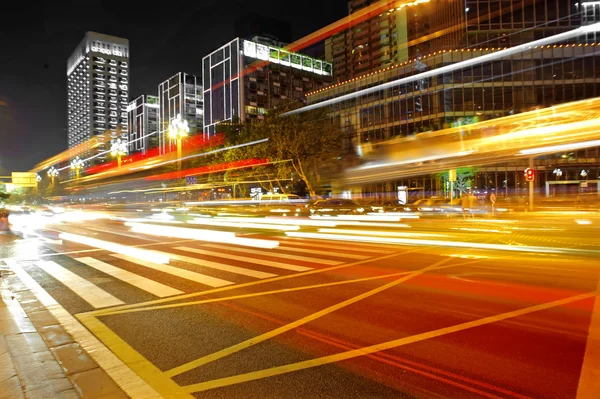 Sentieri leggeri per autobus ad alta velocità e sfocati nel paesaggio notturno del centro — Foto Stock
