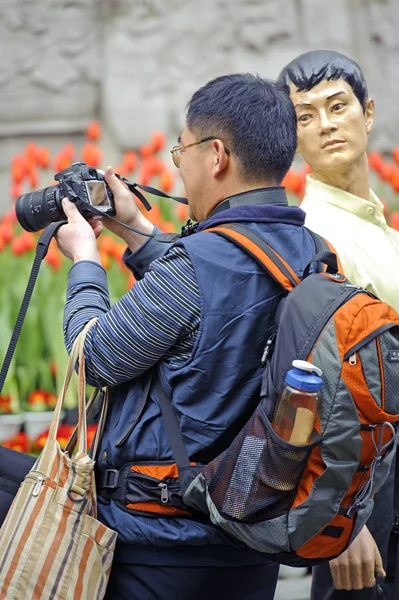Muž s fotografii vedle socha muže — Stock fotografie