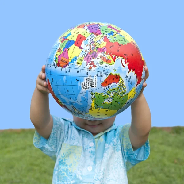 stock image Boy holding the earth model on the grass