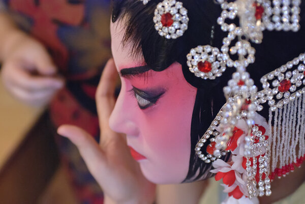 A chinese opera actress is painting her face