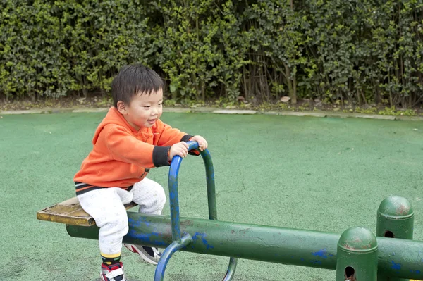 Bebê jogar seesaw em um parque infantil — Fotografia de Stock